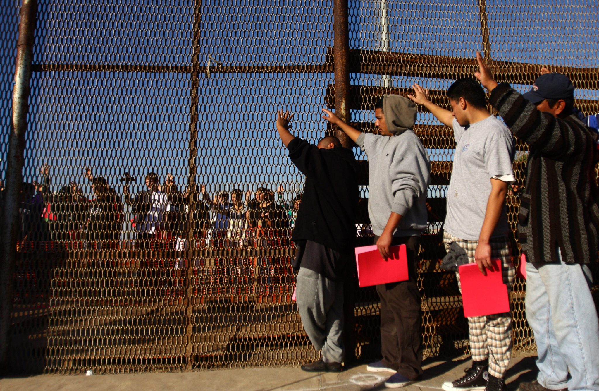 A group of recently deported immigrants stand near the double steel fence that separates San Diego and Tijuana at the border in Tijuana December 10, 2011. Immigrants rights organizations from the U.S and Mexico on Saturday organized an annual pre-Christmas celebration called "Posadas sin Fronteras" or "Christmas without borders", which more than 200 people from both sides attended on the Tijuana and San Diego border. REUTERS/Jorge Duenes (MEXICO - Tags: SOCIETY IMMIGRATION)